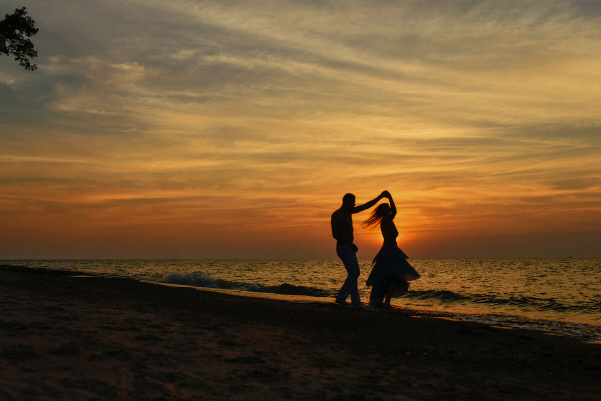 Engagement silhouette picture of young love birds dancing in the sunset at the beach during golden hour in Indiana