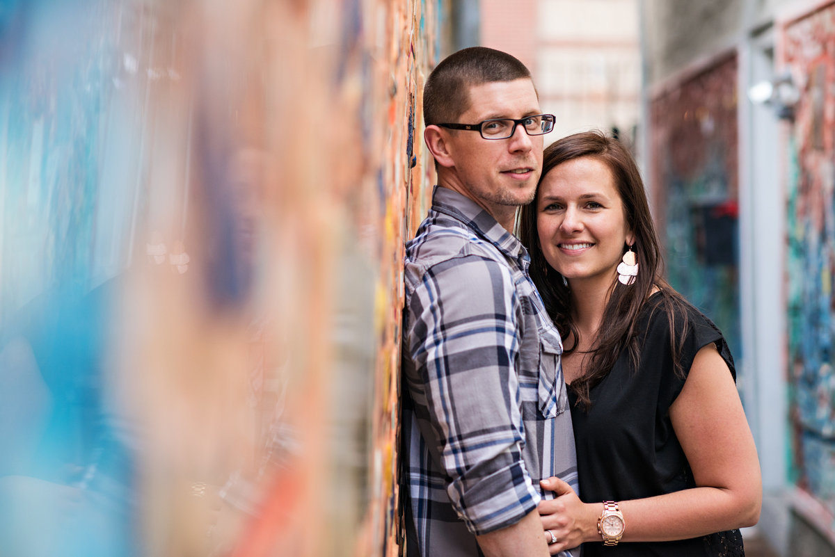 A happy couple lean against a south street wall covered in glass and shiny objects.
