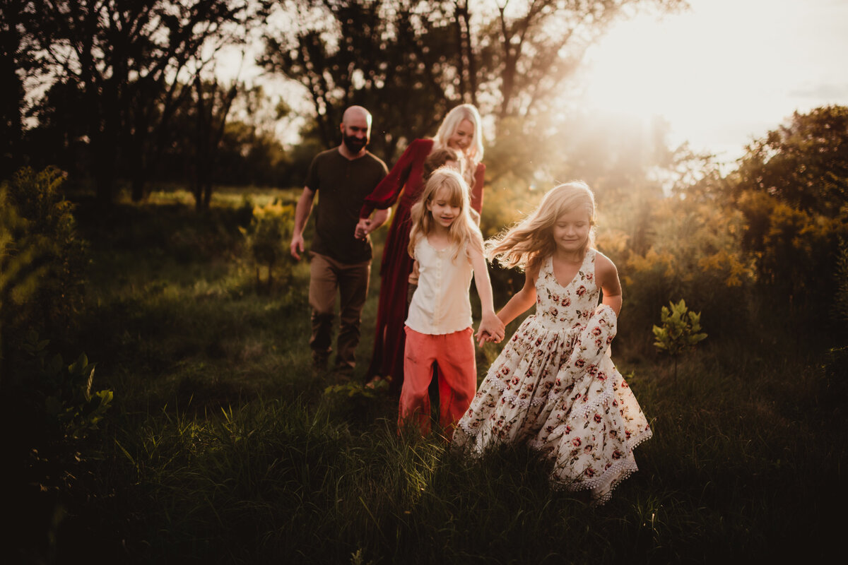 Family of 5 holding hands and walking through a field