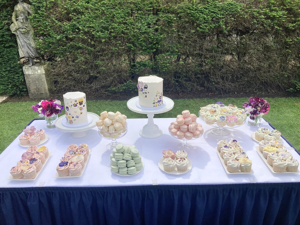 Elegant dessert table with cupcakes macarons and edible flower cakes in Oxford