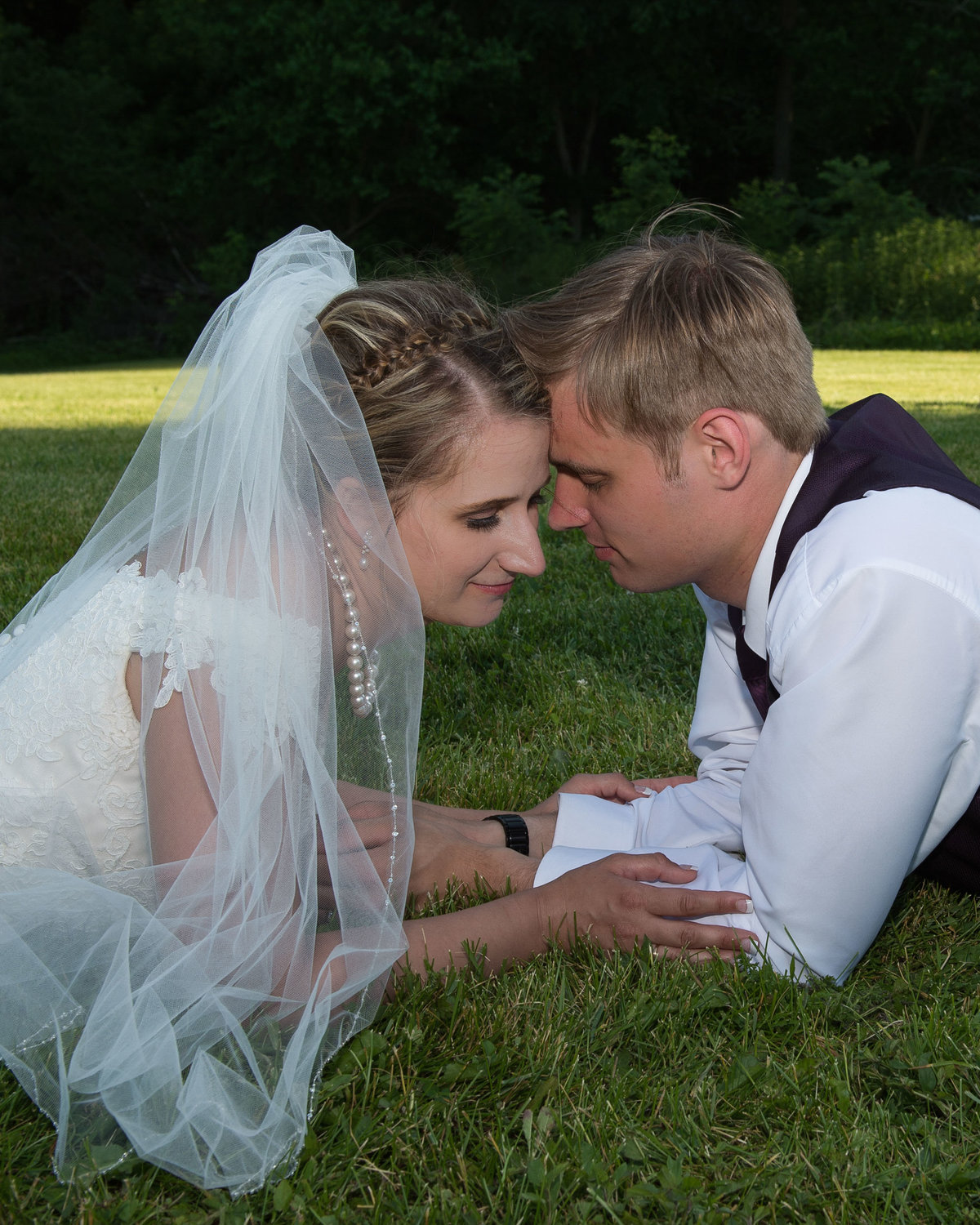 bride wears full beil and pearls posed in grass