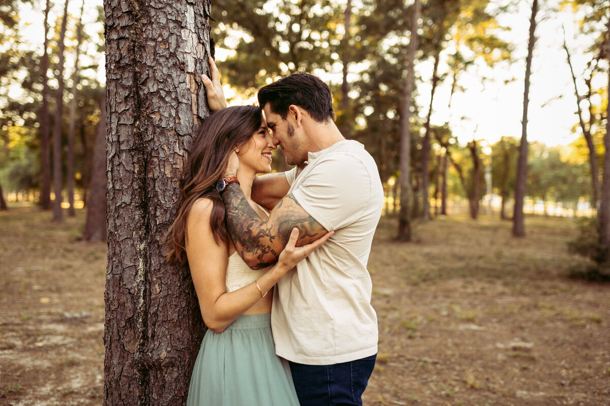 husband kisses and snuggles wife in natural outdoor couples session in panama city fl