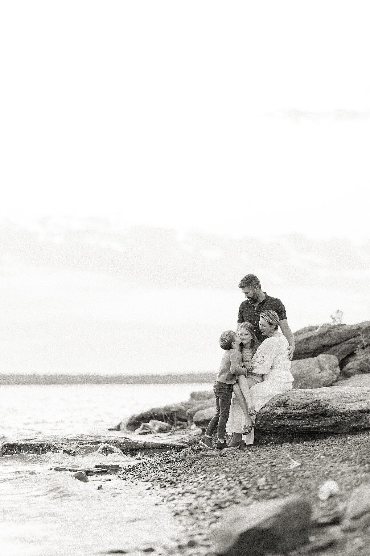 A beautiful black and white family photo as they are posing on rocks at a local DFW lake for their photographer.