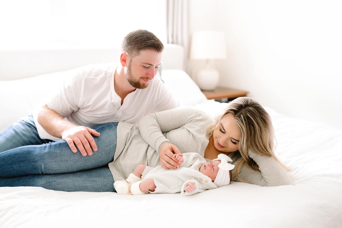 Couple lying on bed gazing at newborn