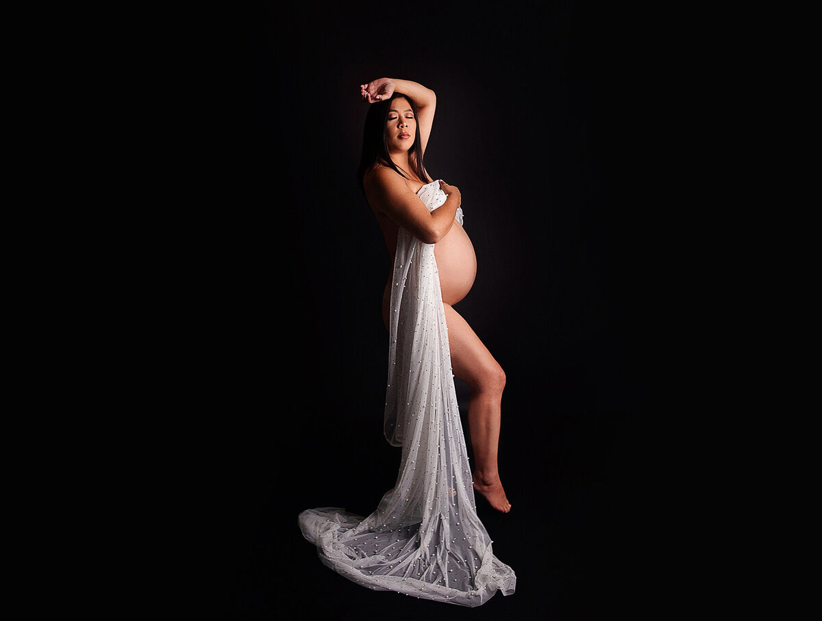Women posing naked with sheer fabric draped over belly during maternity photoshoot in Mount Juliet Tennessee photography studio
