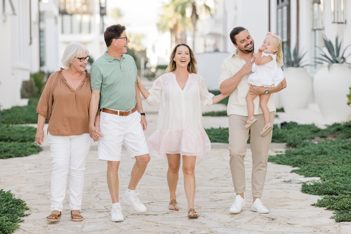 A family holding hands and smiling as they walk along a path