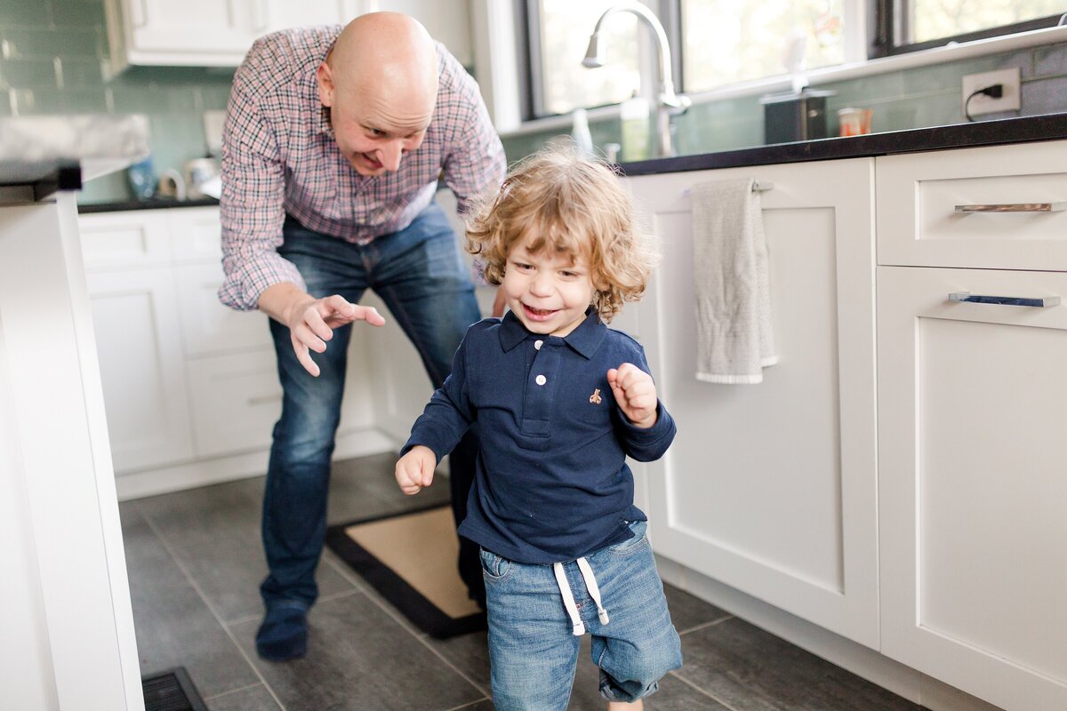 A father and son playing in a kitchen during an in-home lifestyle family session  in Lexington KY.
