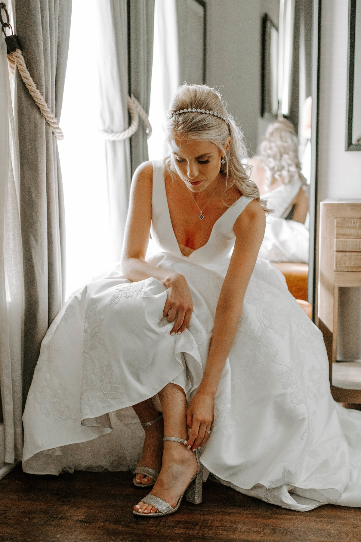 A bride sitting on a stool as she puts on her shoes