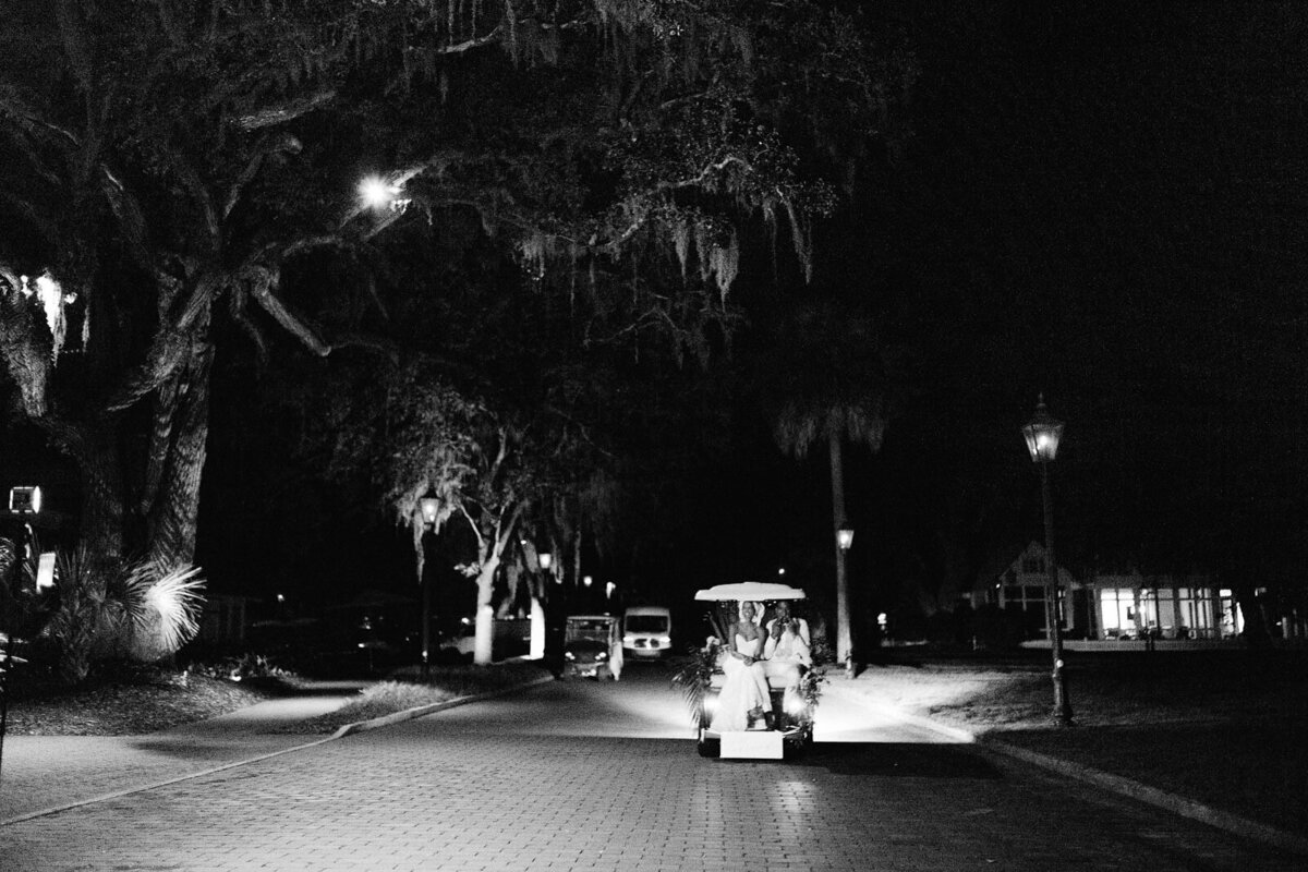 The bride and groom are riding a golf cart after the wedding in Montage at Palmetto Bluff. Destination Image by Jenny Fu Studio