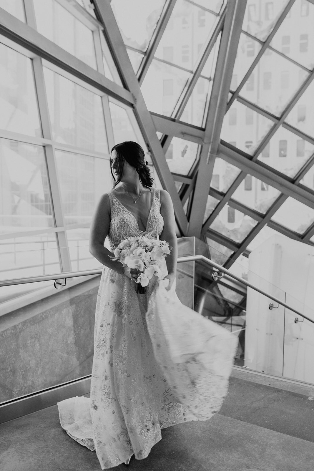 Black and white photo of the bride in her wedding dress looking out the window.