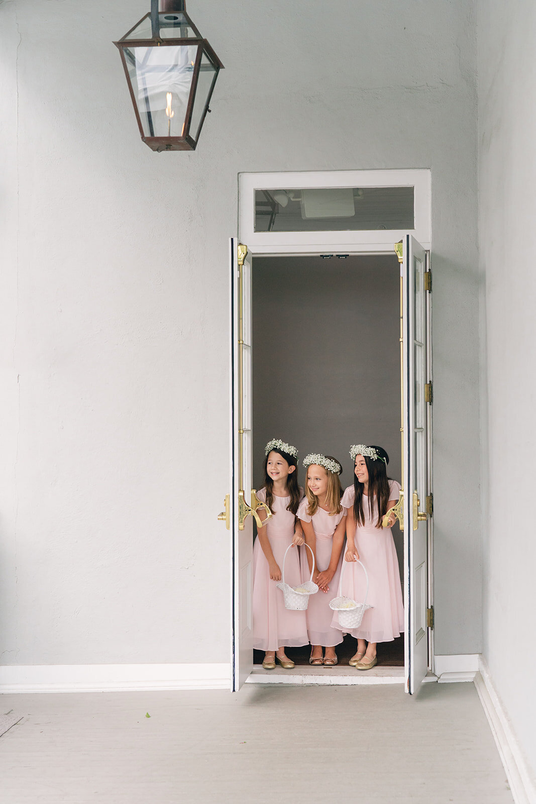 Cute flower girls in pink peek out at the wedding ceremony at Gadsden House spring wedding in downtown Charleston.