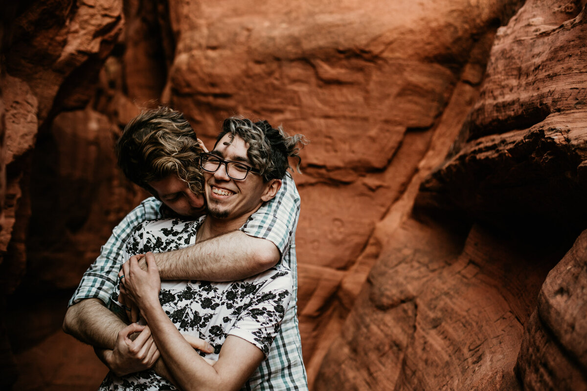gay couple holding each other in canyon