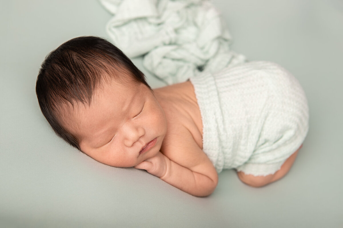 Bum up newborn pose on a mint backdrop