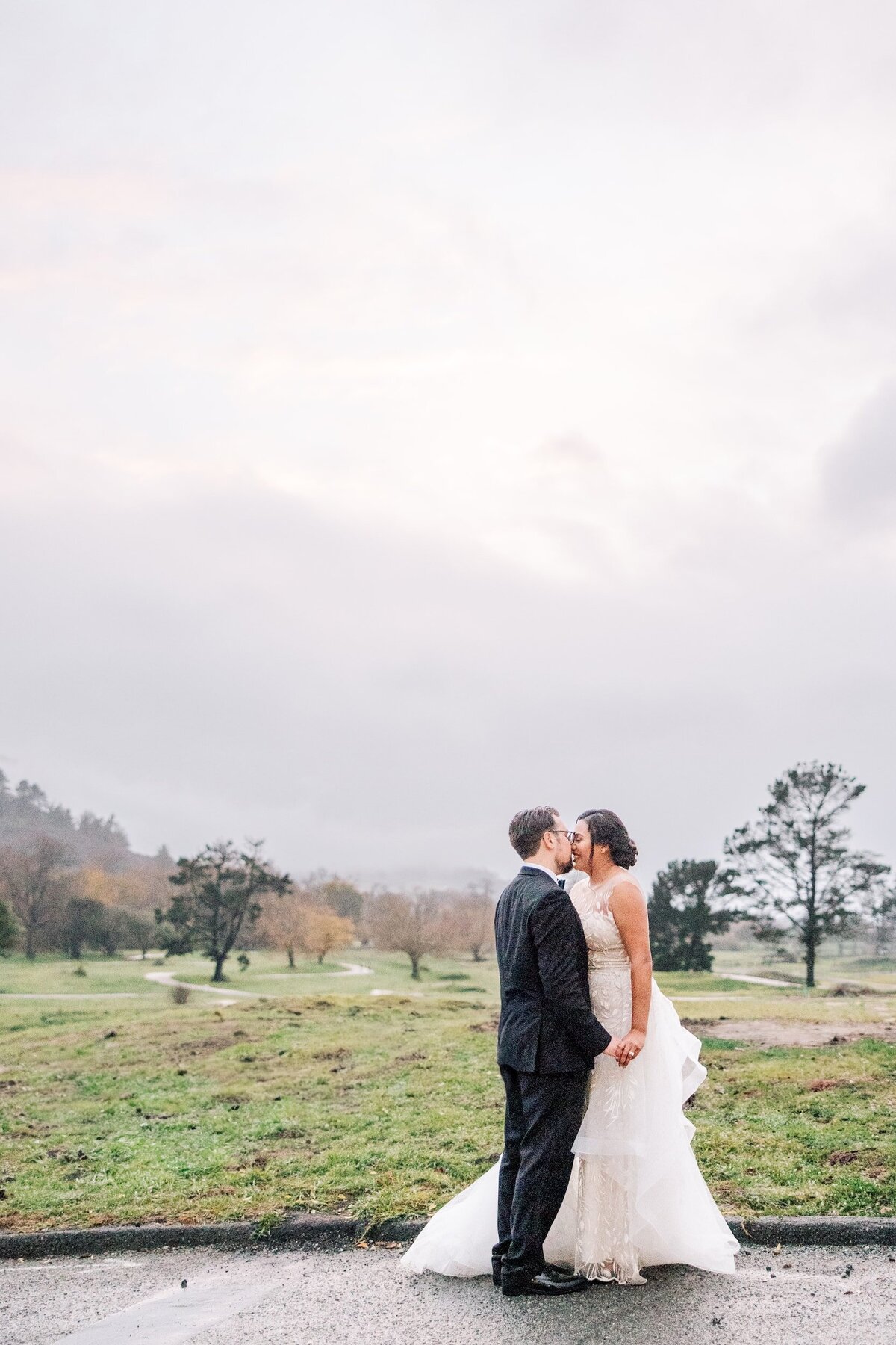 Bride and Groom Kissing during dramatic sunset foggy rains