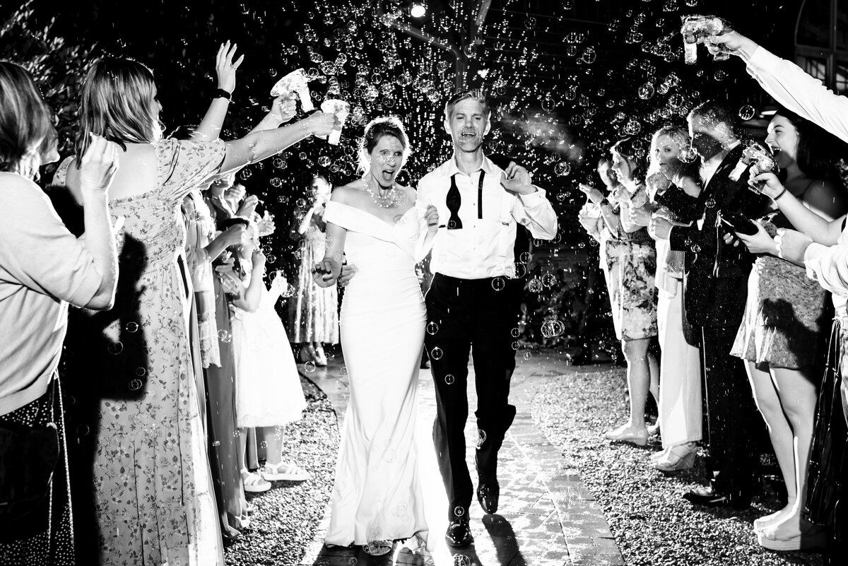 Black-and-white-image-of-a-couple's-candid-reaction-during-their-wedding-bubble-exit-their-at-Alexander-Homestead