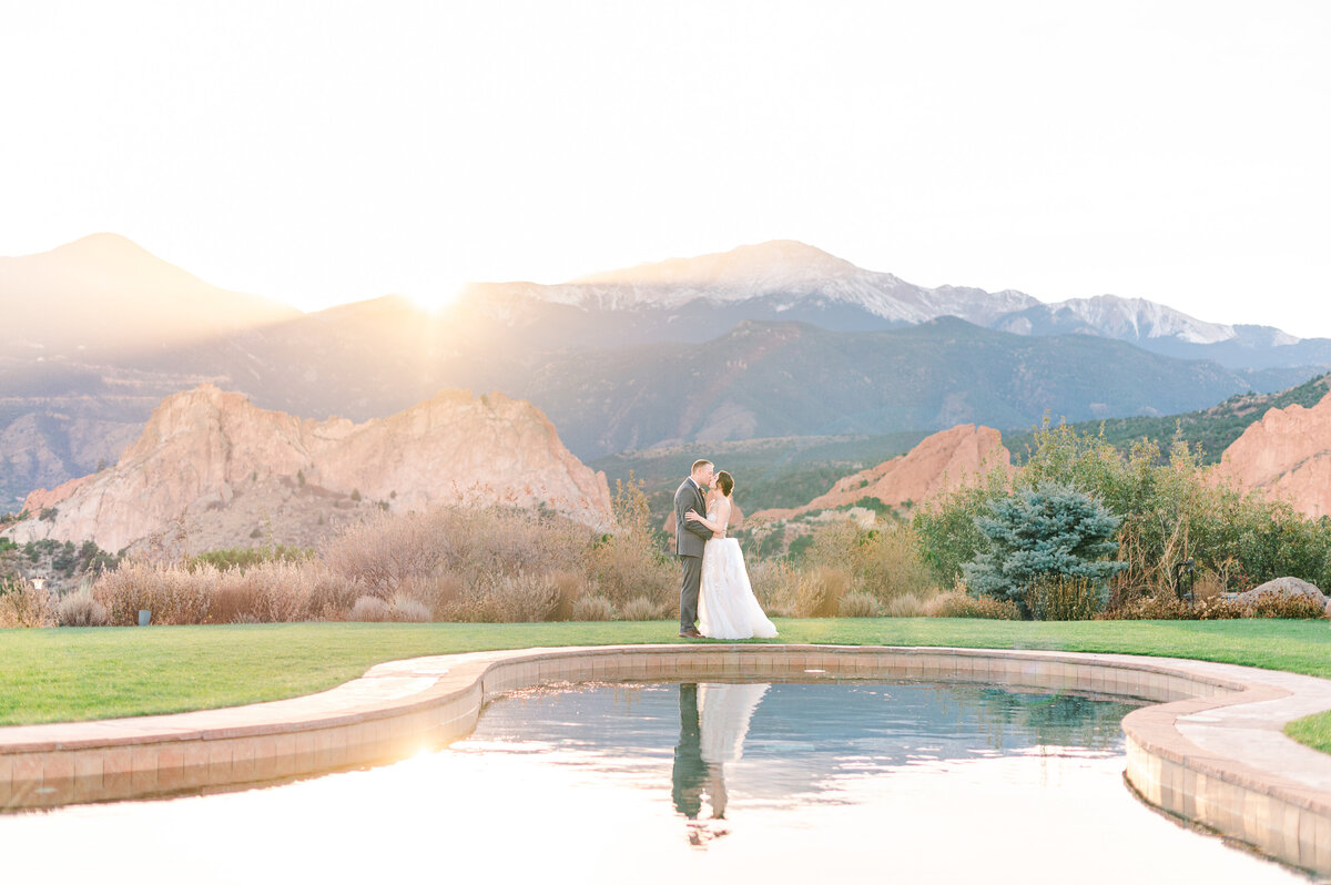 Sunset portrait of a couple kissing in front of the reflection pool at Garden of the Gods Resort and Club.