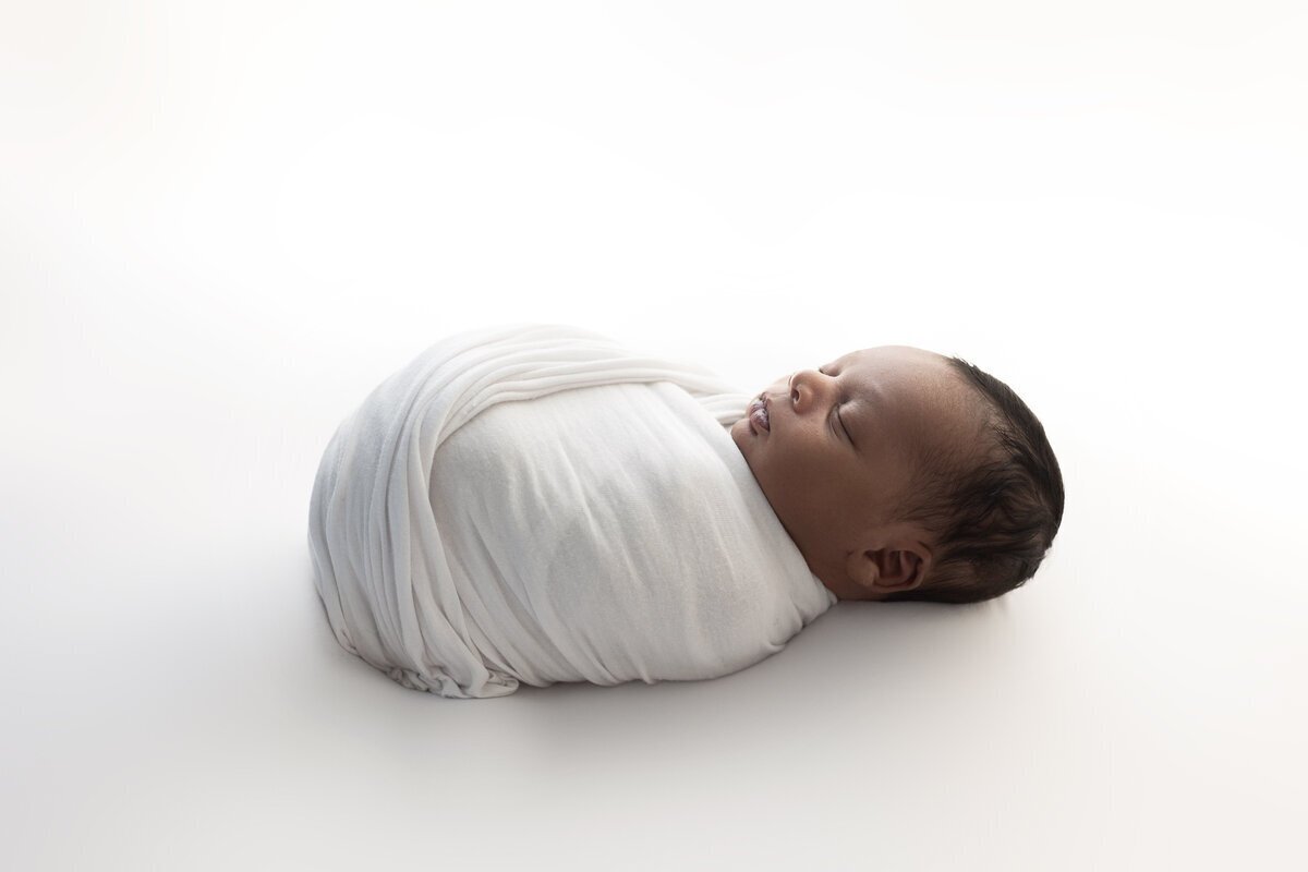 newborn photography in new jersey of baby swaddled on bean bag