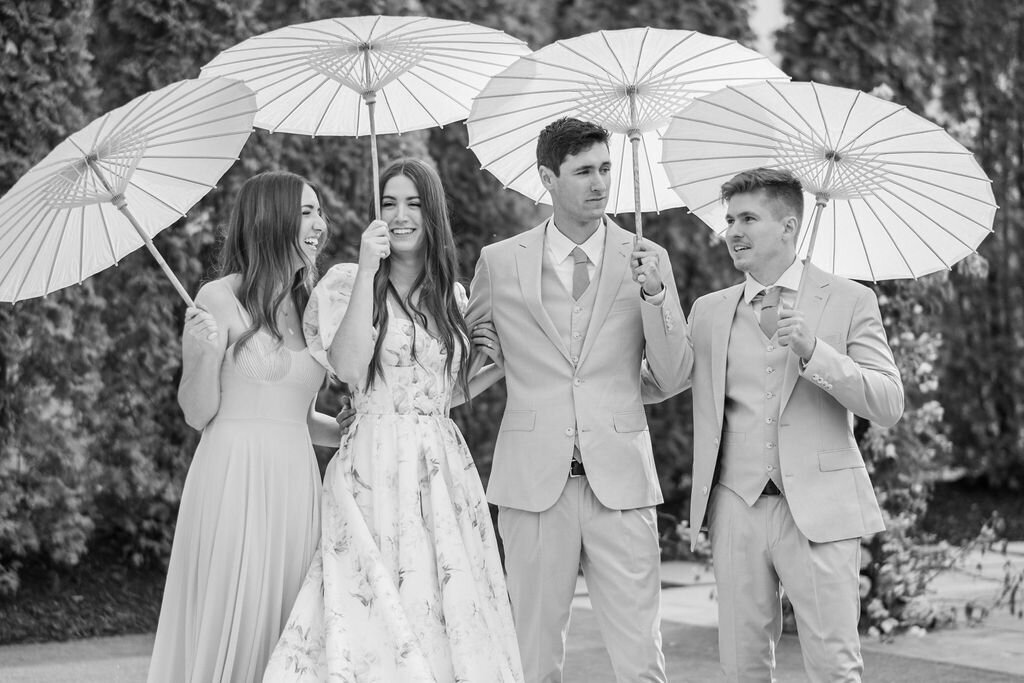 Bridal party holding delicate paper umbrellas during garden wedding portraits
