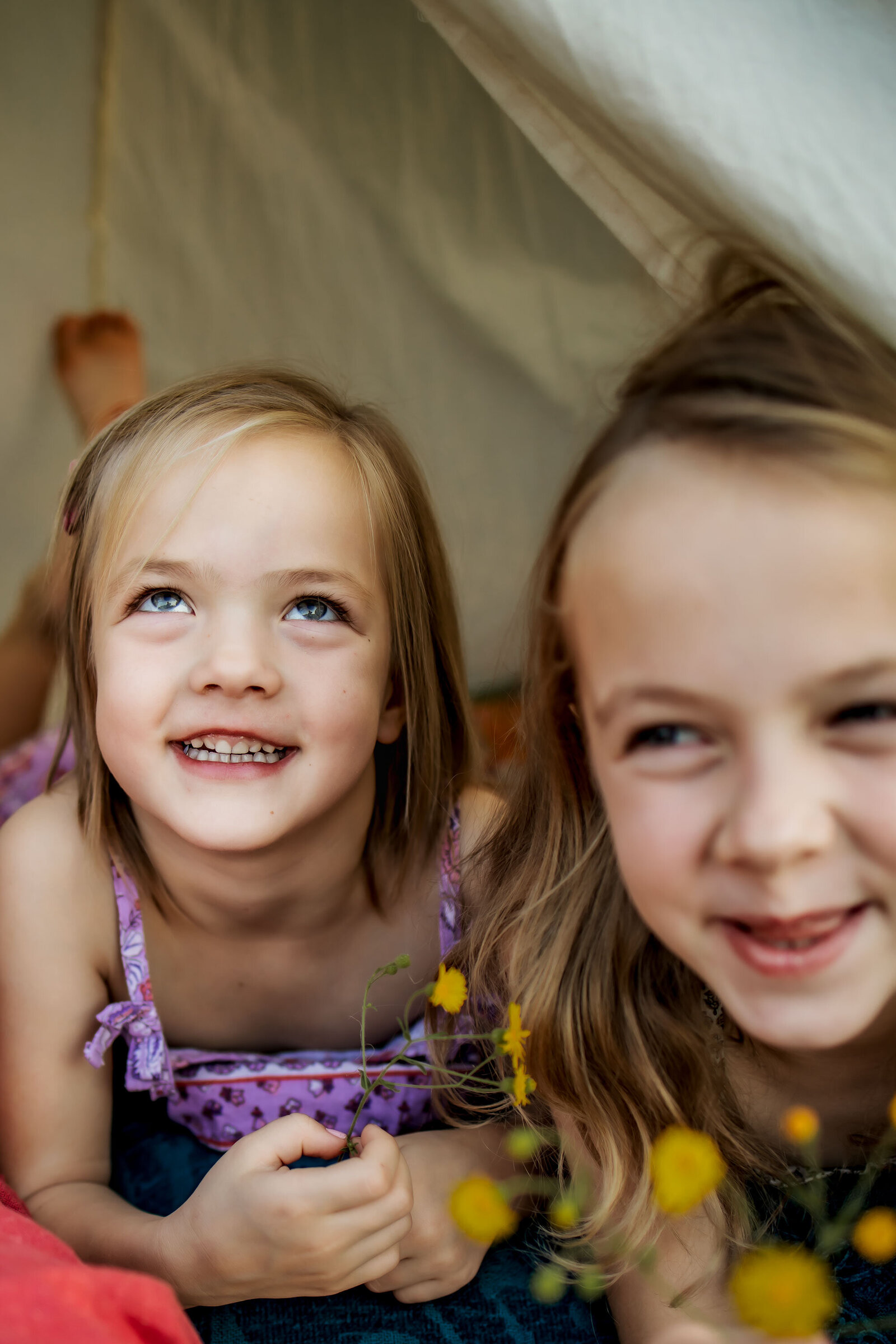 sisters laughing in a play tent in the texas wild flowers