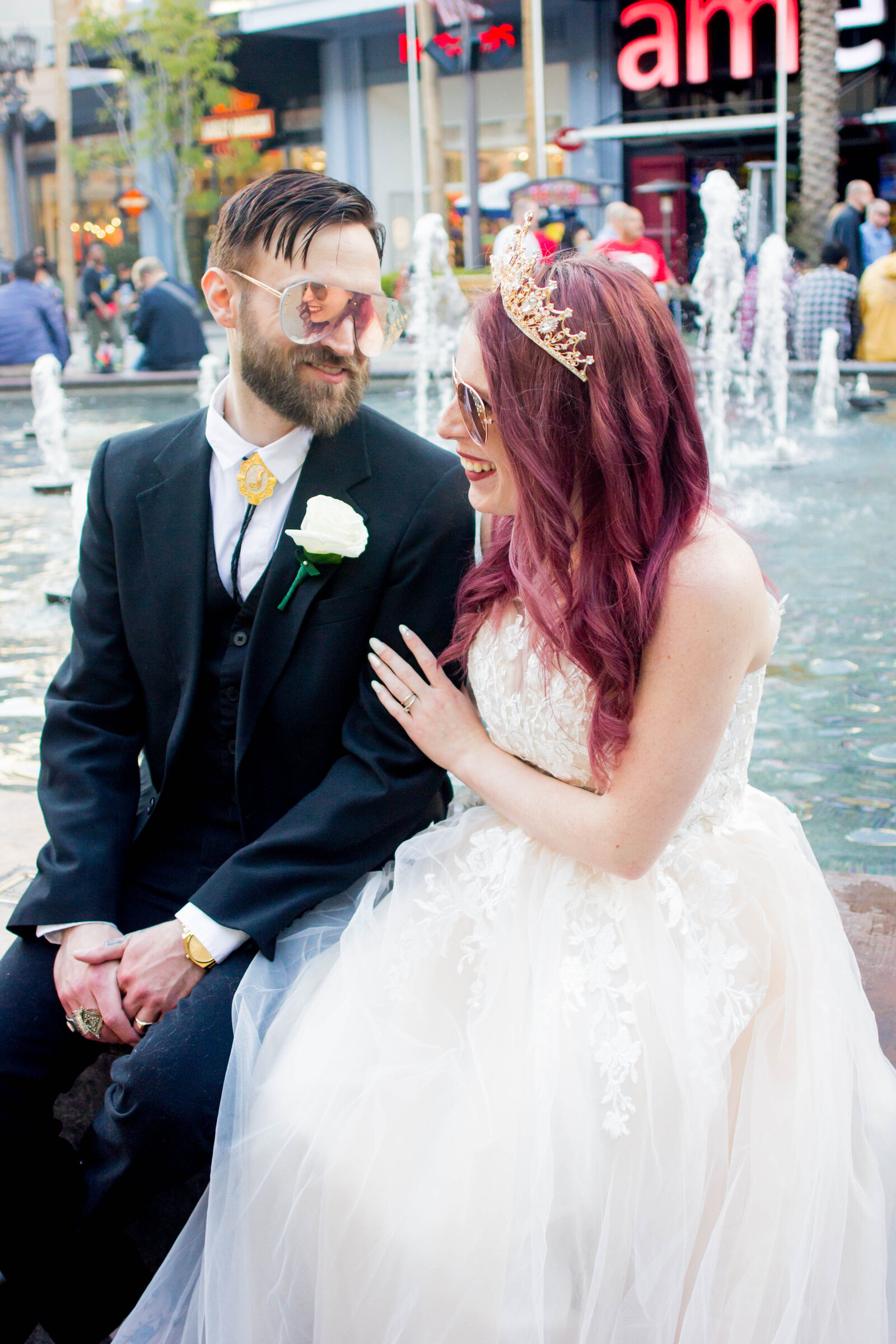 A man and woman on their wedding day sitting on a fountain in Las Vegas.