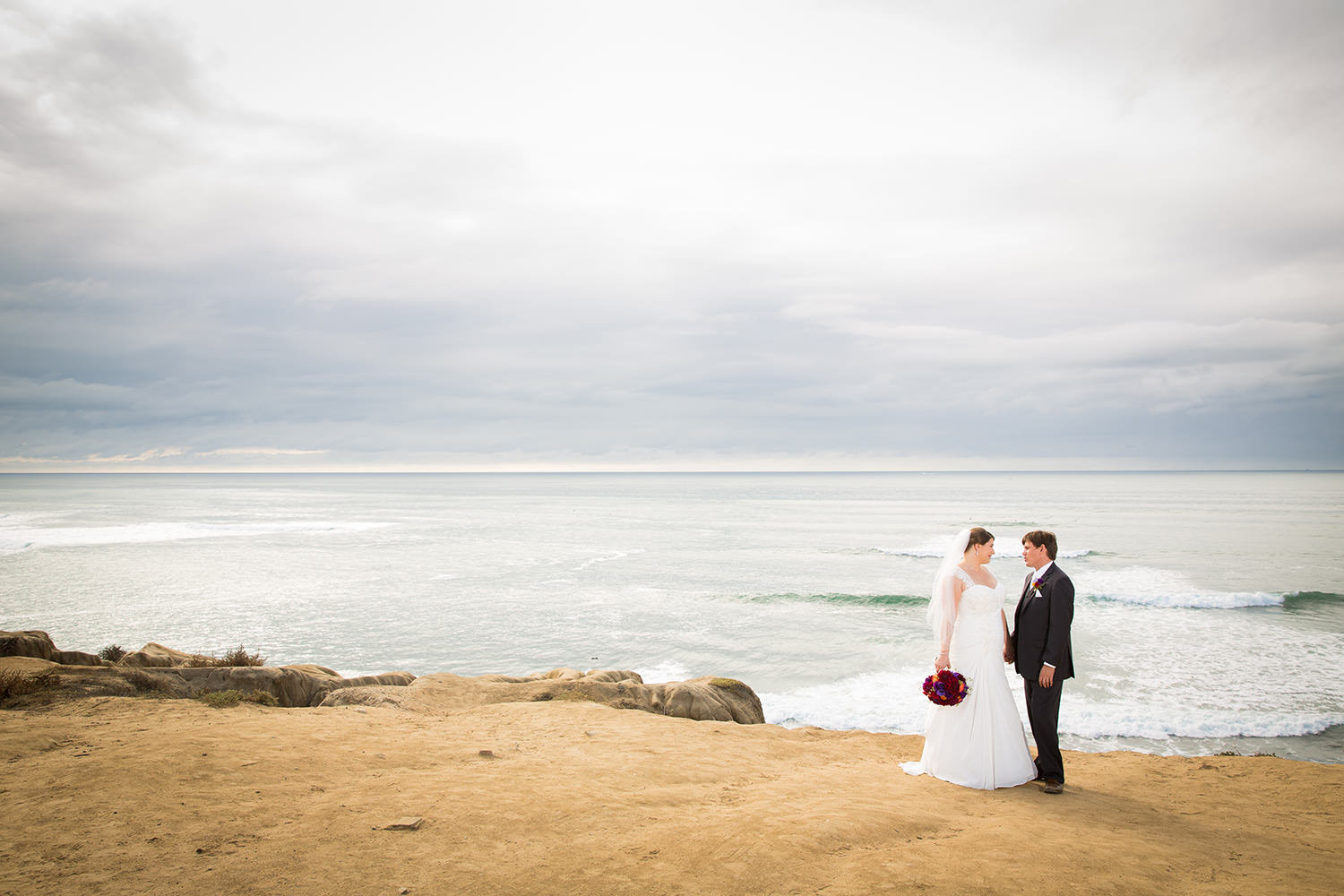bride and groom with ocean in back ground
