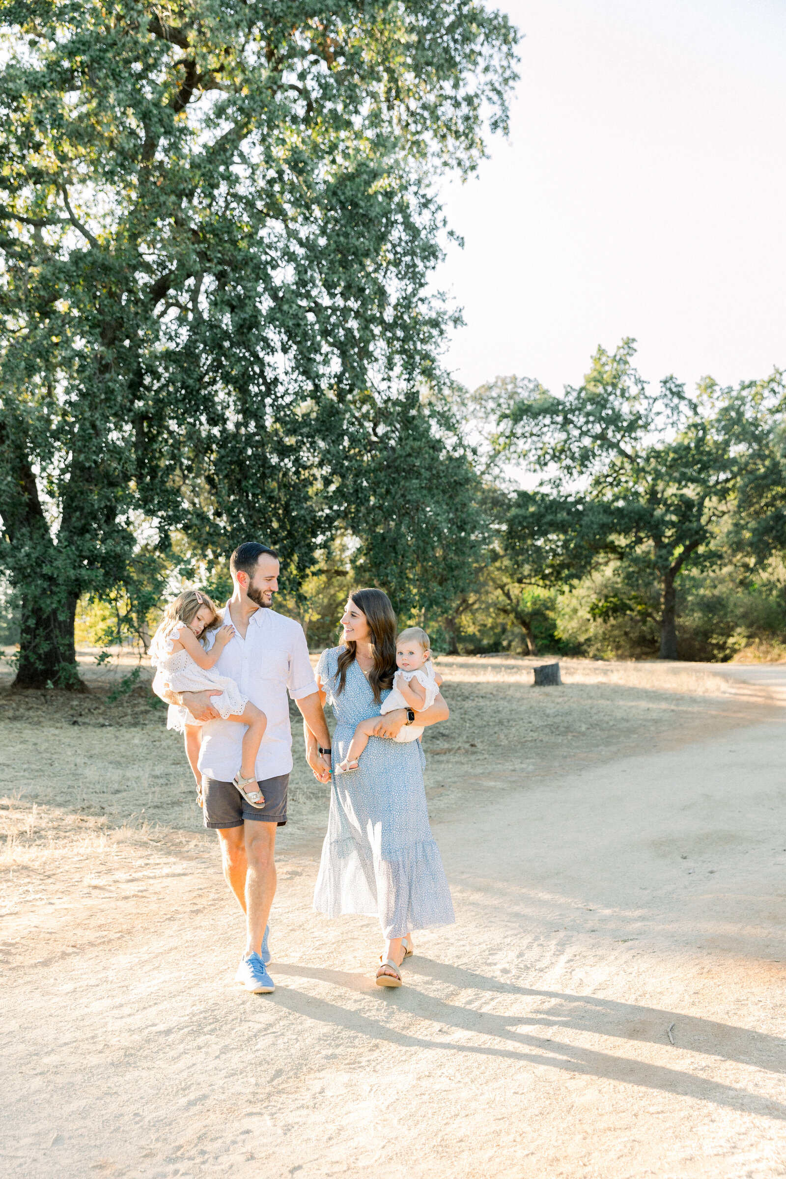 Image of family walking along trail together holding hands taken by Sacramento Newborn Photographer Kelsey Krall