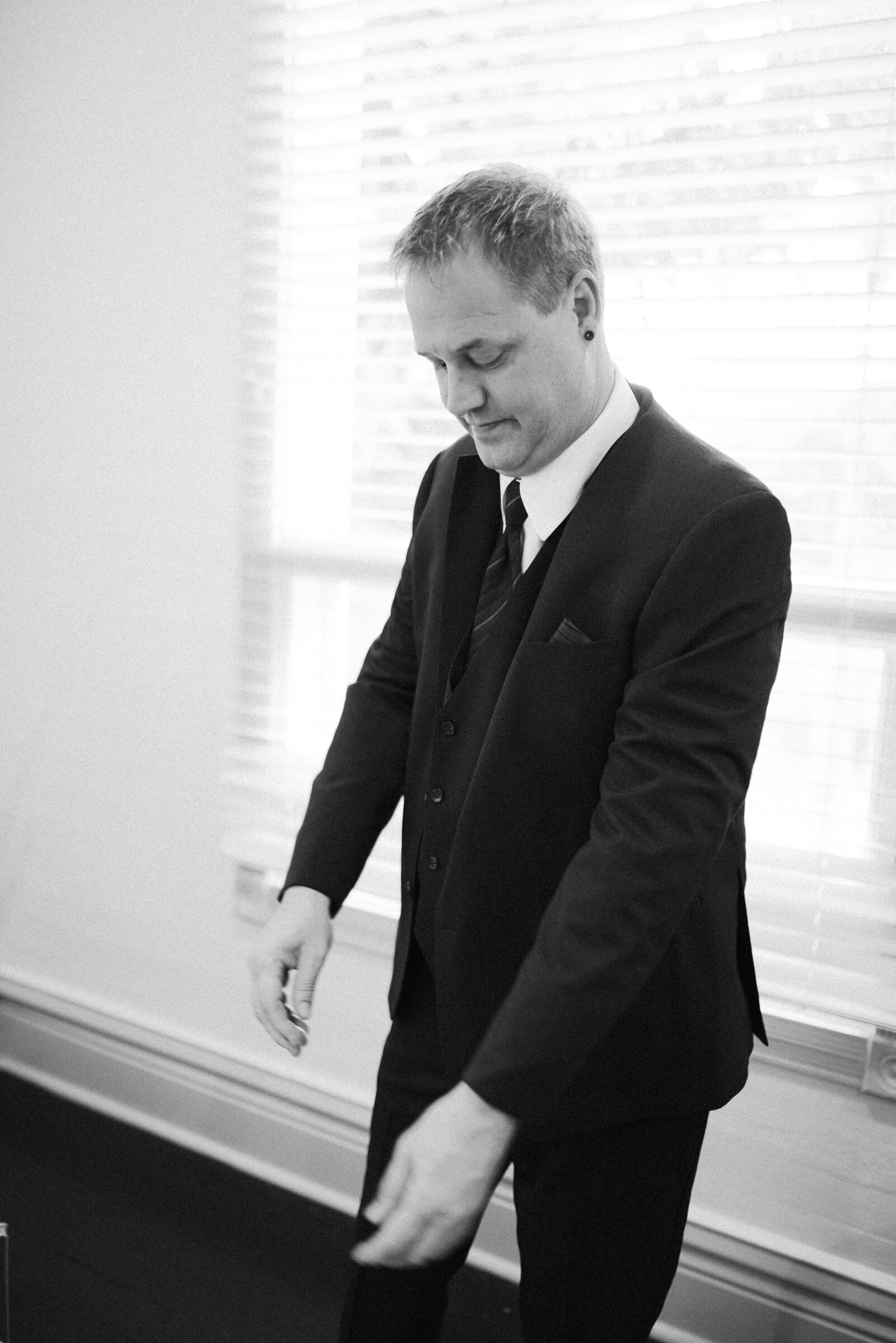 Groom adjusting his suit jacket sleeve in his dressing room