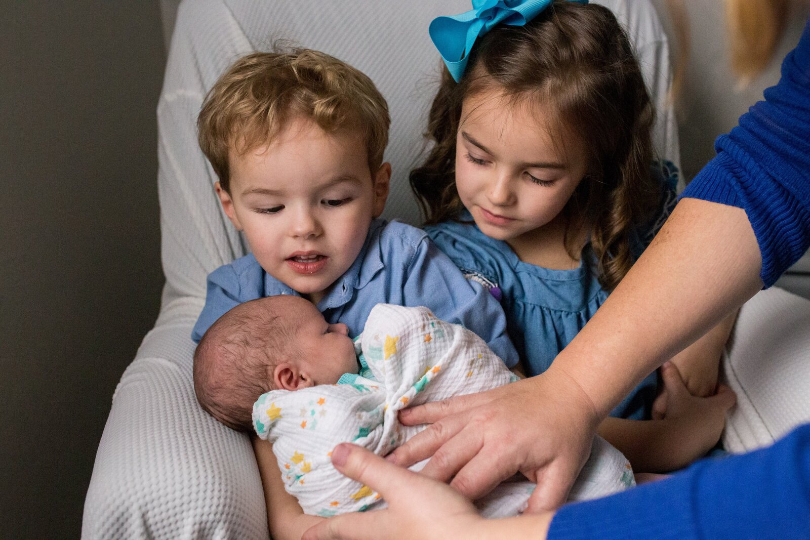 Brother and sister holding newborn brother
