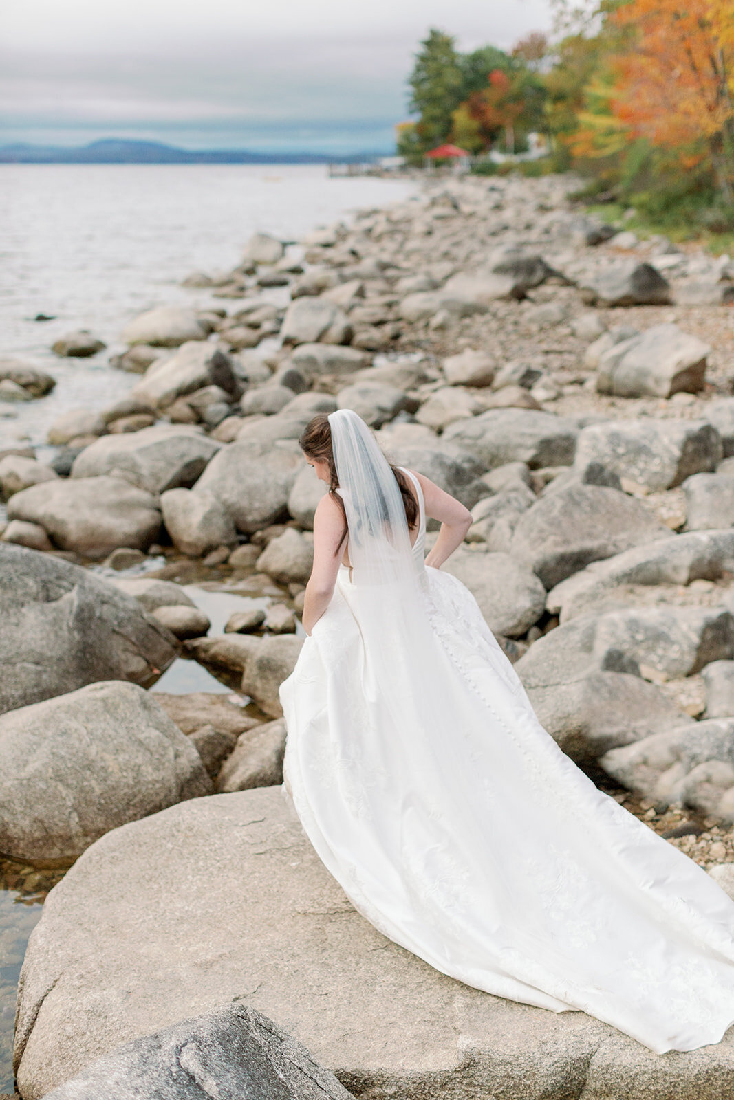 Bride walking along a rocky shoreline.