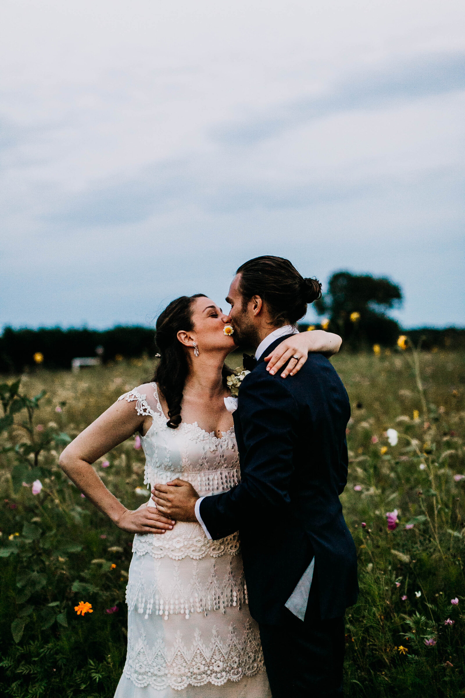 bride and groom kissing in flower field