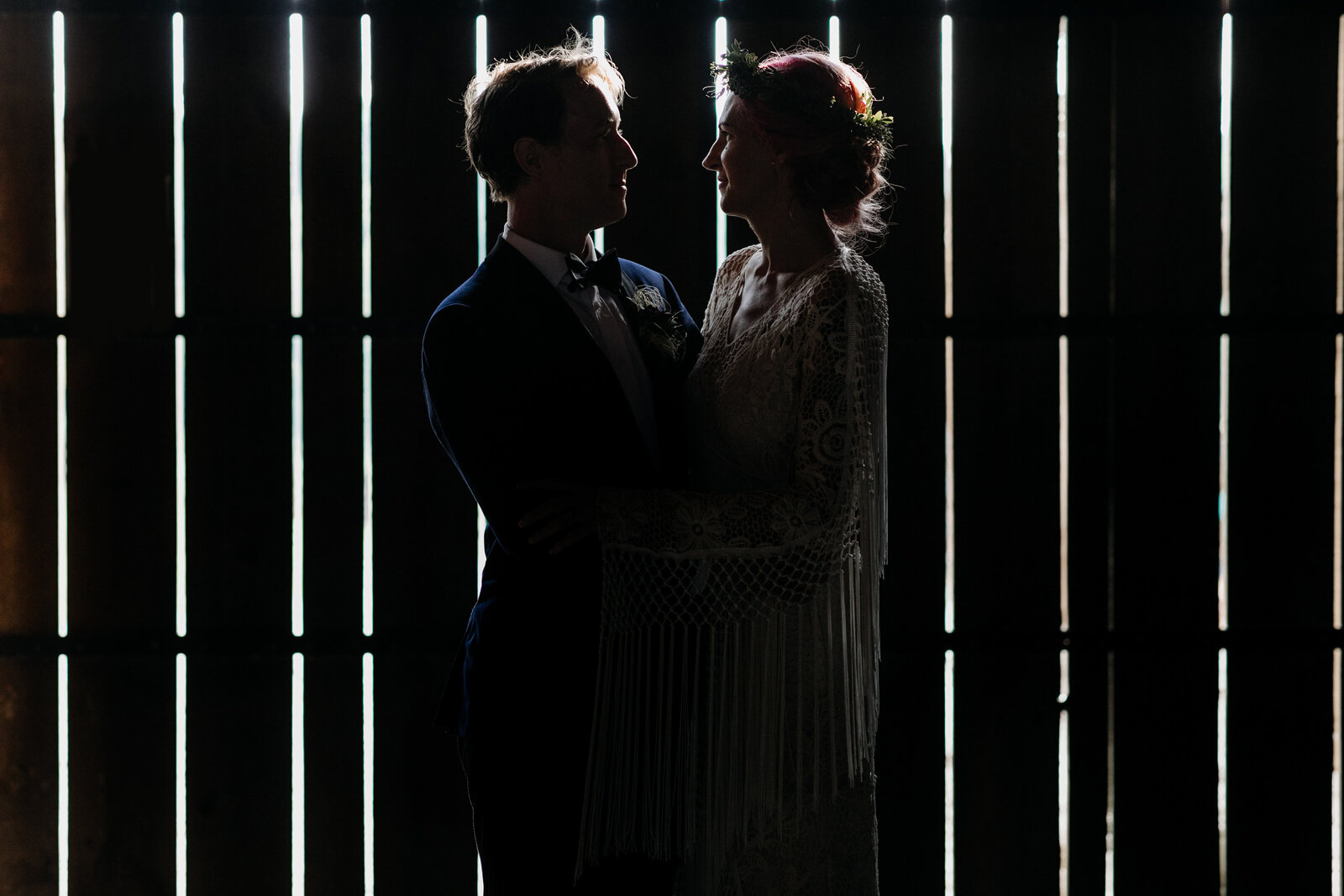 bride and groom in moody barn light