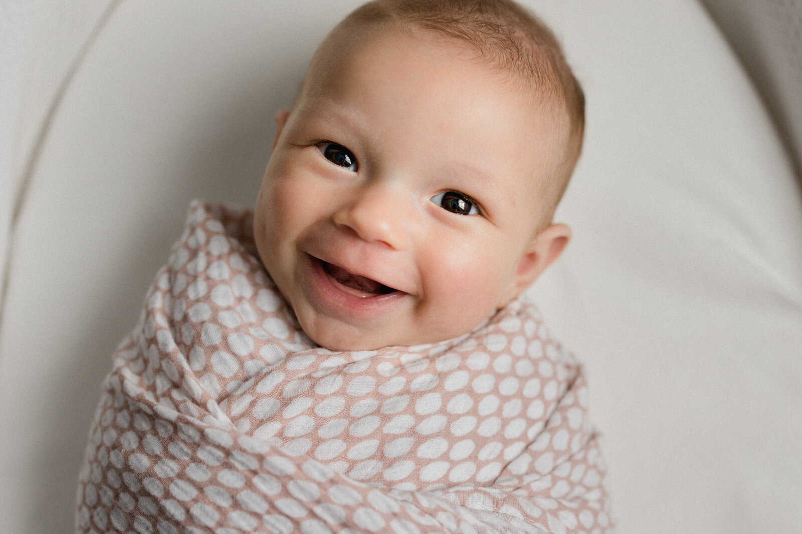 Six month photos of a smiley new baby looking at the camera
