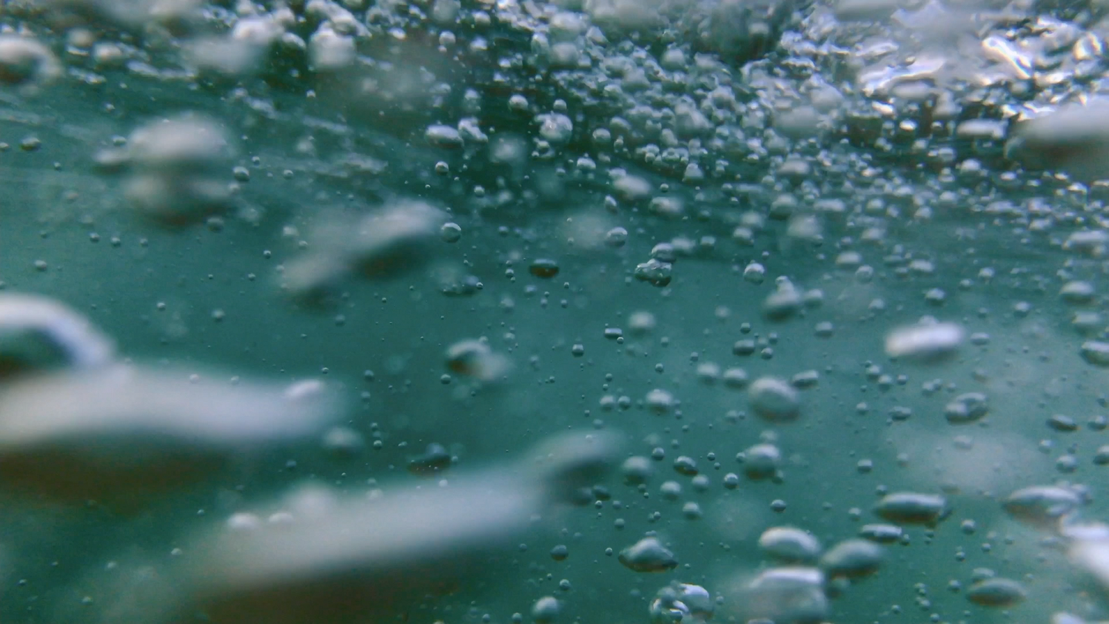 Perspective from under water with air bubbles rising toward the surface