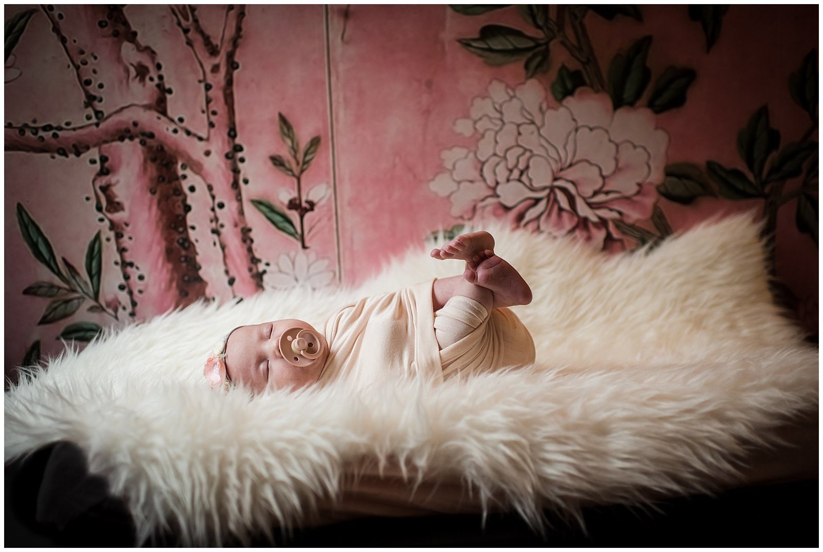 Newborn baby girl on sheepskin with pink floral Magnolia wallpaper moody Emily Ann Photography Seattle Photographer