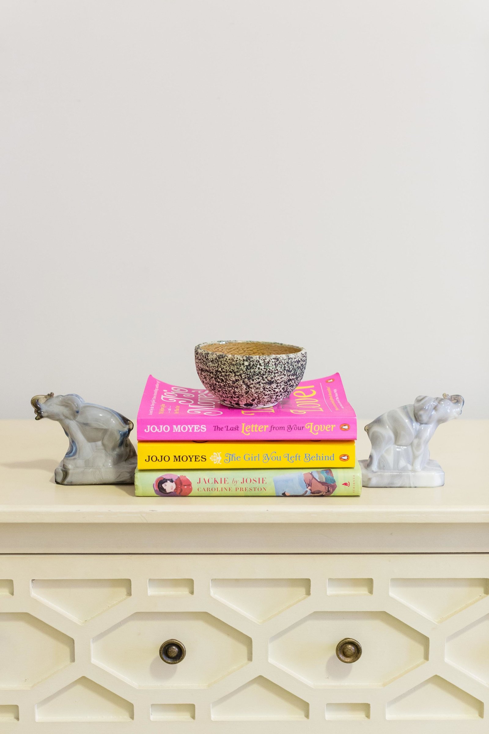 Books, ceramic dish, and bookends on a dresser.