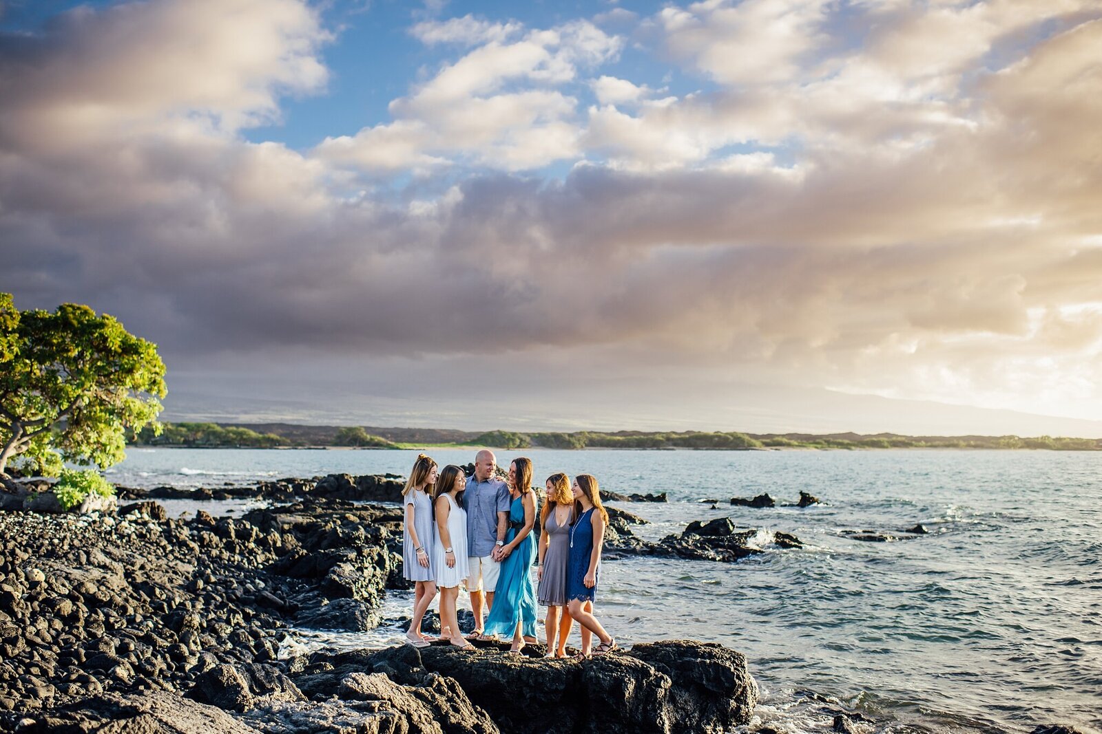 family on lava rocks with stunning hawaii sunset