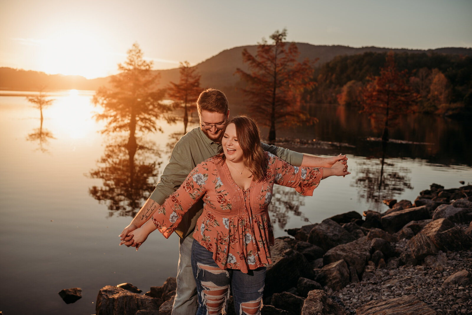 photo of man and woman waving their arms in front of a pond