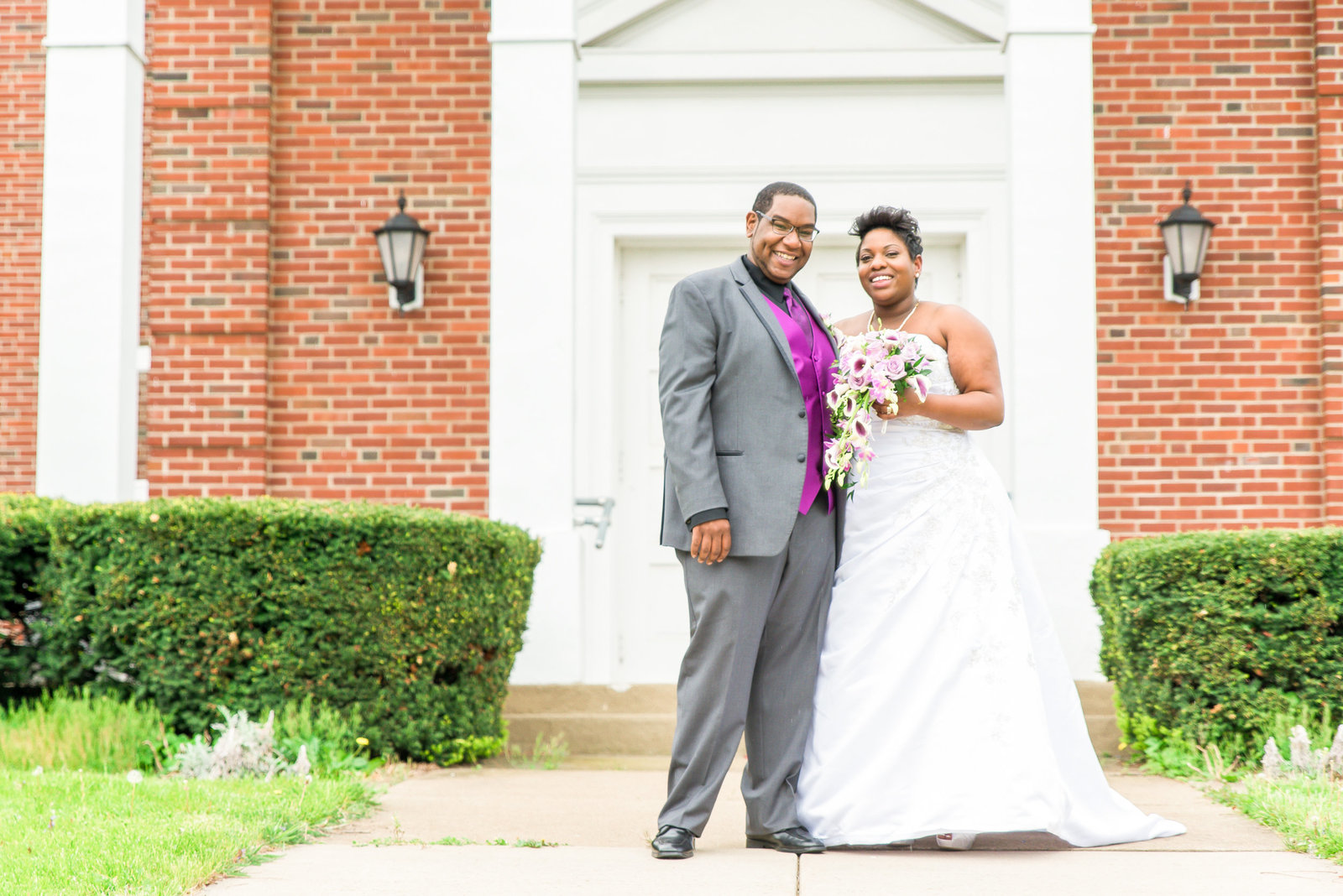 Couple poses in front of red brick church