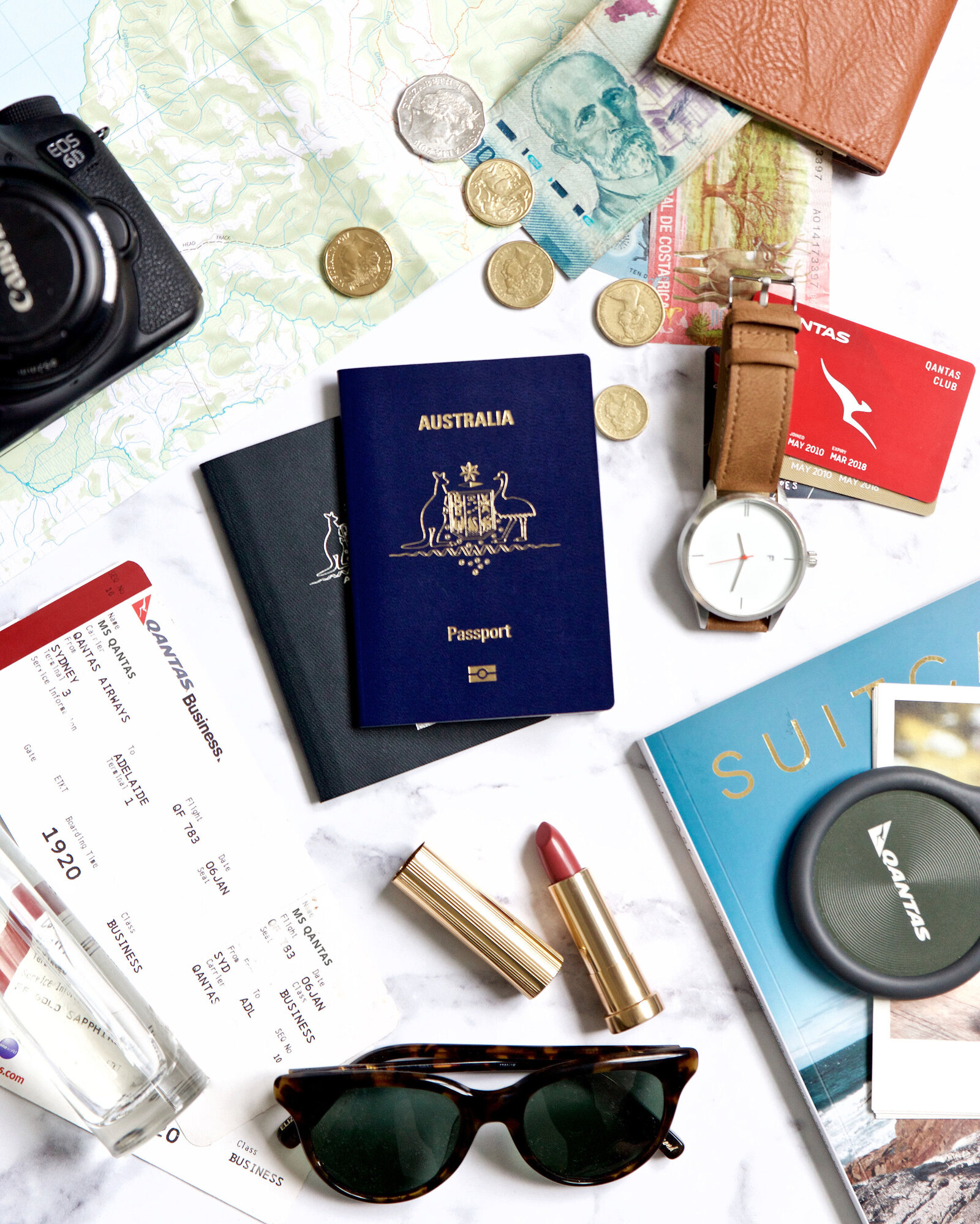 Branding travel photographer Chelsea Loren styled travel flat lay for Qantas Australia with passports, coins, plane tickets, watch, camera, sunglasses