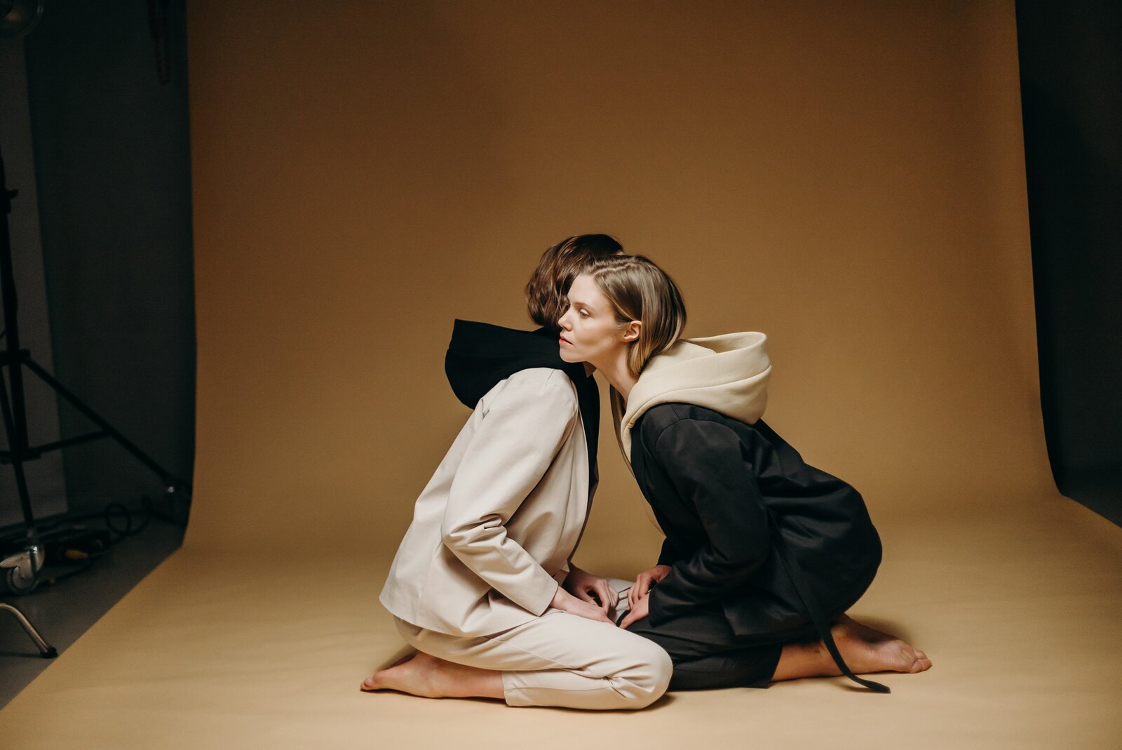 woman-in-black-blazer-and-white-pants-sitting-on-brown-floor-3917695