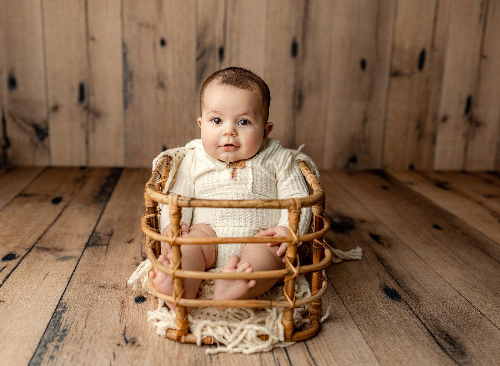 4 month old baby boy sitting in a basket for his milestone photography session.