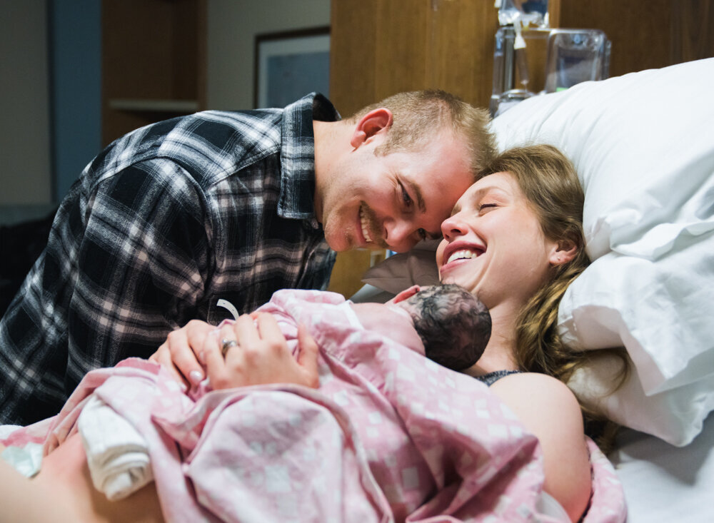 Parents smile at the arrival of their new baby girl. Utah hospital photos.