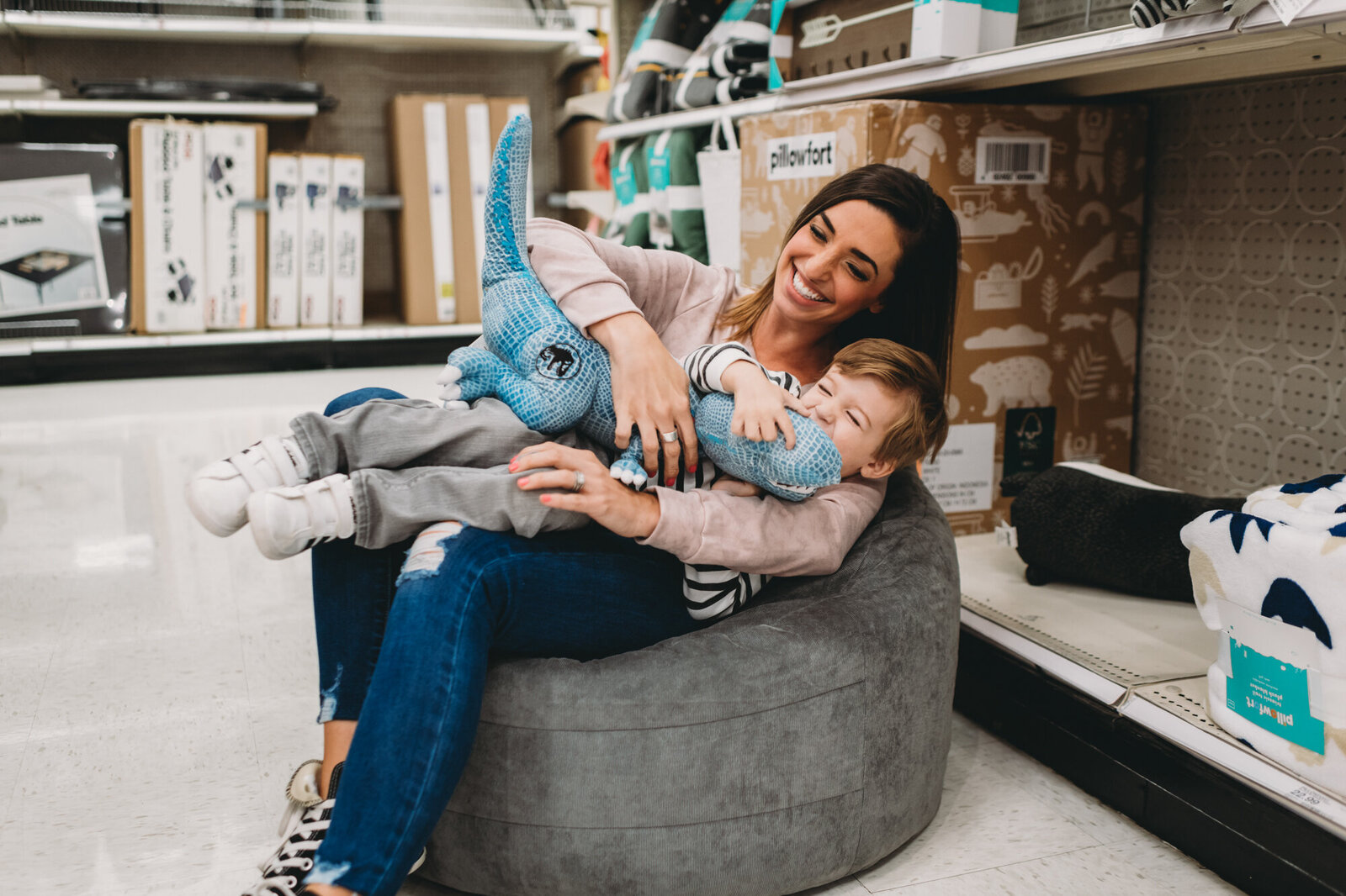 Branding Photographer, a mother sits with her toddler boy on a ottoman at the store