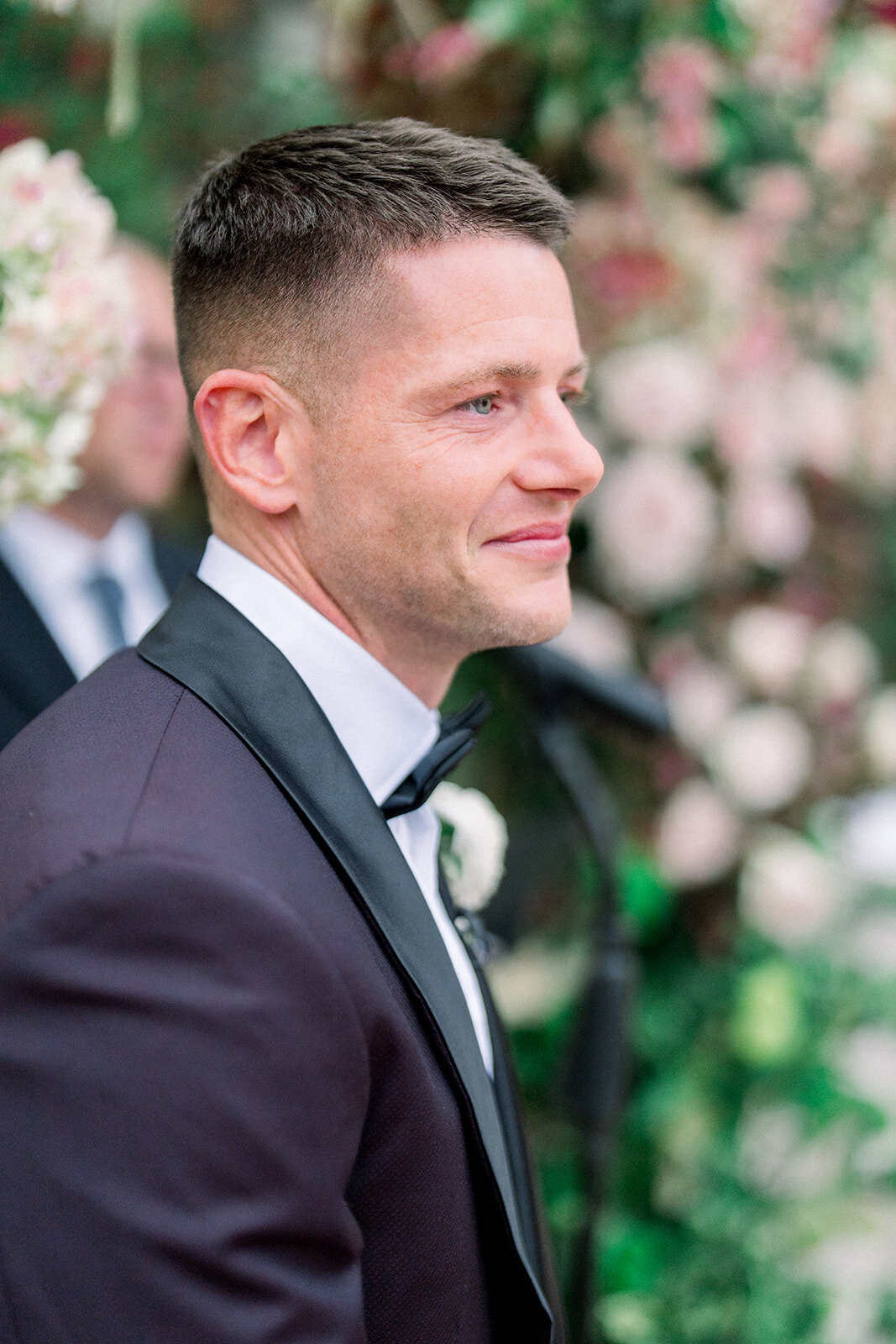 Handsome groom smiling in a classic tuxedo during ceremony, captured in soft film tones at Hummingbird Nest Ranch.
