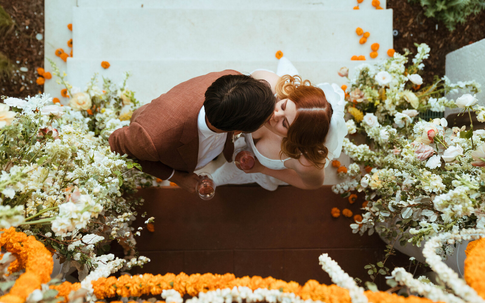 A couple kisses beneath a large Anthousai floral installaion.
