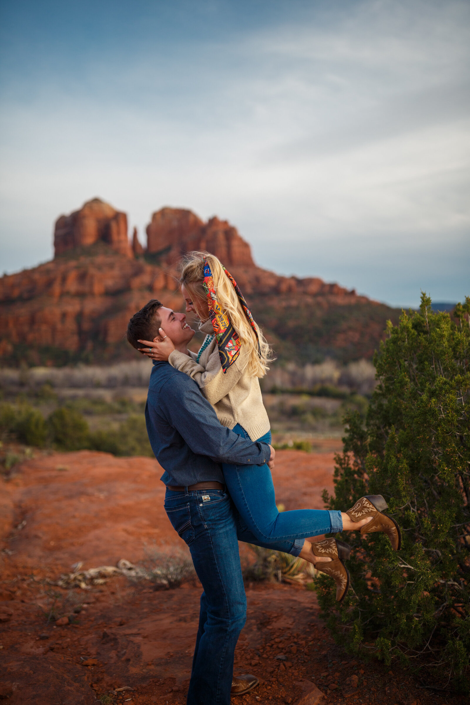 candid couple kissing in front of red rocks