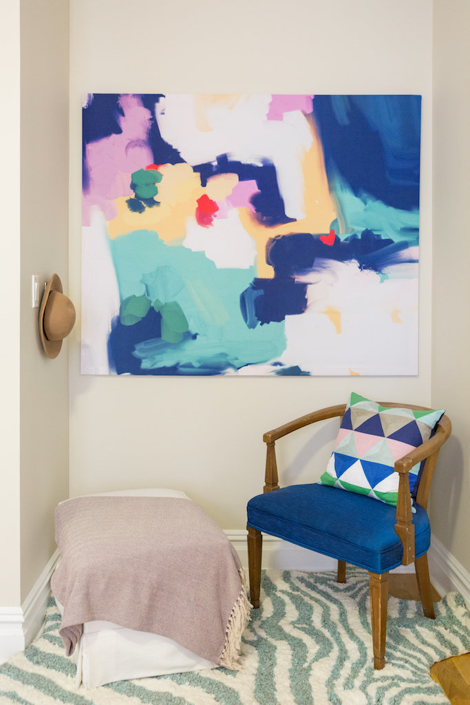A blue chair and ottoman and bright abstract painting.