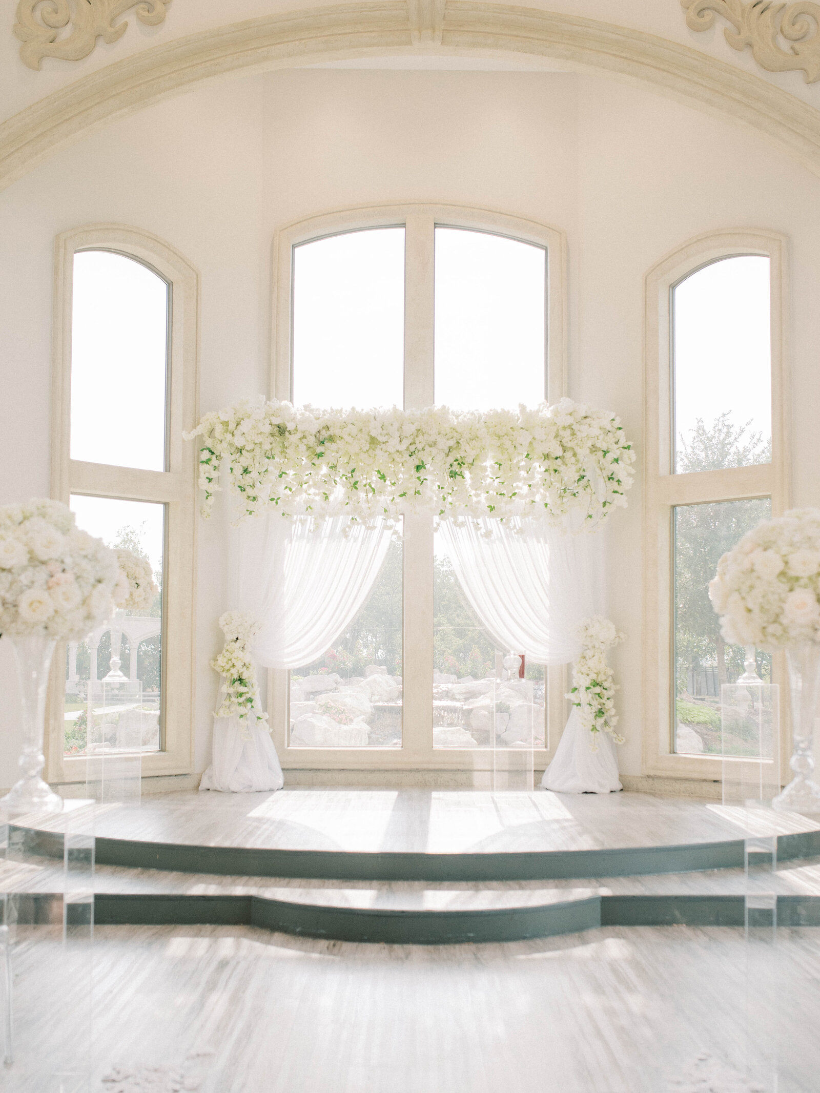 Grand church alter with white floral arrangements and white tapestries