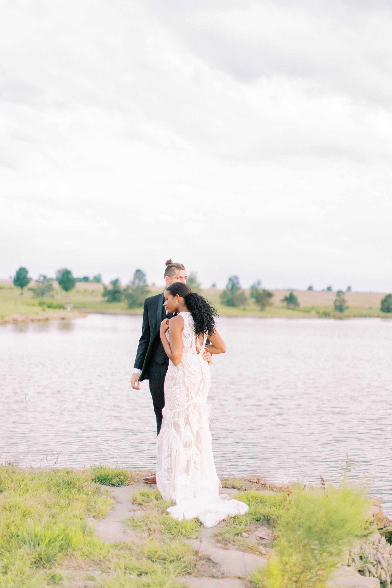 Bride and groom share moment by the lake at Bourgmont Winery in Kansas sunset
