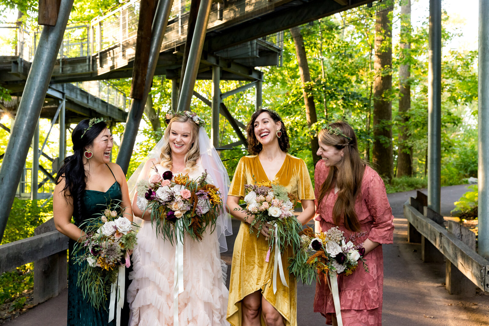 A photo capturing three bridesmaids and the bride laughing together, in a half-circle in a garden setting in Philadelphia.